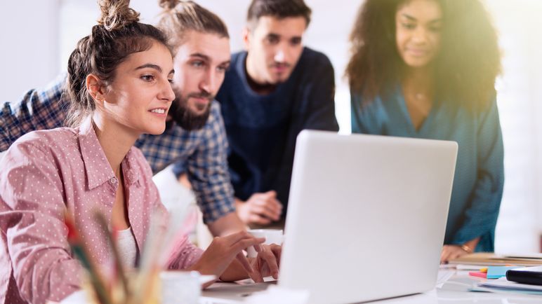 Eine Gruppe von Lernenden tauscht Ideen zu einem Projekt rund um einen Computer aus