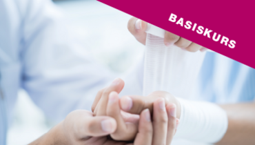 Ein Bild von einem Handgelenk, welches von einer Pflegekraft mit einem Verband verbunden wird – im Blickfang steht "Basiskurs"